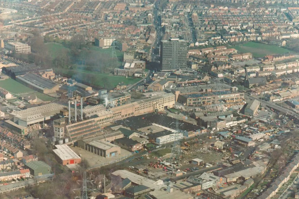 Aerial photo showing dense industrial buildings, car lots, skip yards, and derelict land west of Christchurch Road in Colliers Wood.